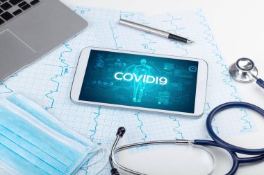 COVID19 yazıtları, koronavirüs kavramına sahip tablet bilgisayar ve doktor araçları
