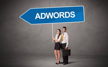 Üzerinde ADWORDS yazıları, yeni iş yönü konsepti olan günlük bekleme yolu tabelasında genç bir iş adamı