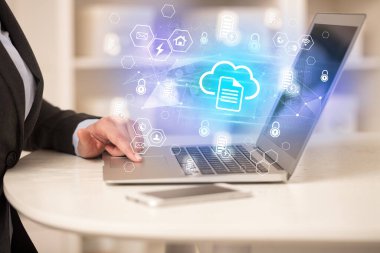 Eller dizüstü bilgisayarda bulut depolama simgeleri ve modern teknoloji konseptiyle çalışıyor.