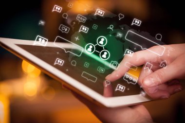 İçinden insan bağlantısı simgeleri çıkan tablet kullanan bir elin yakın plan resmi, sosyal medya kavramı