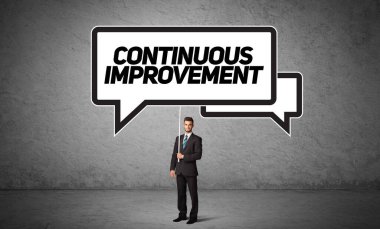 KONTINUOUS İMPROVEMENT yazıtları, yeni iş fikri kavramı ile günlük holding yol tabelası genç iş adamı