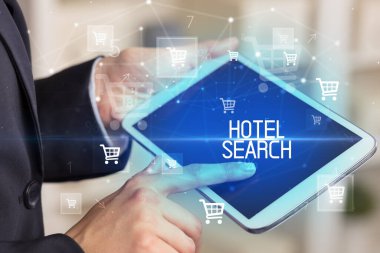 Genç kişi, HOTEL Arama yazısıyla online alışveriş uygulaması üzerinden alışveriş yapıyor