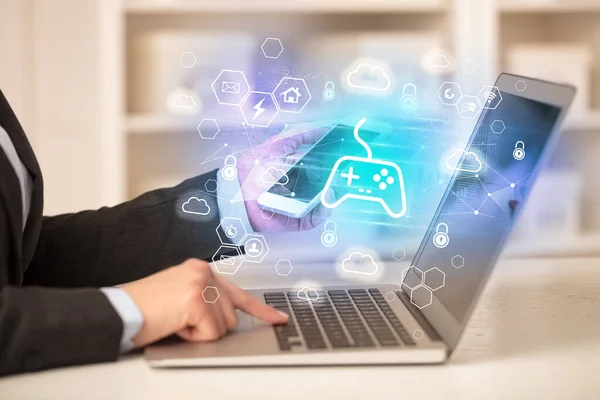 Hands working on laptop with game controller icons, modern technology concept
