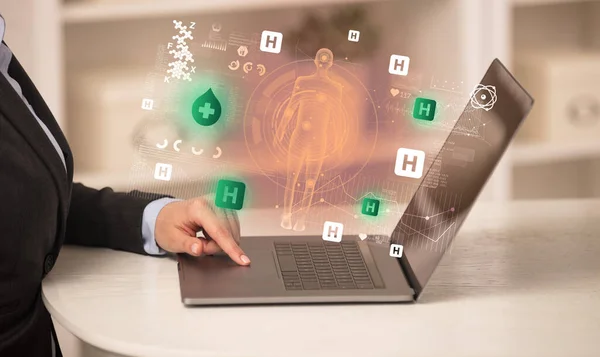 Doctor working on laptop with blood donation icons coming out from it, healthcare concept