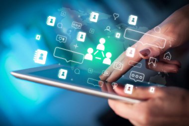 Sosyal iletişim simgeleri içeren tablet kullanan bir elin yakın plan resmi, sosyal medya kavramı