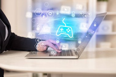 Eller bilgisayar üzerinde oyun denetleyici simgeleriyle çalışıyor, modern teknoloji kavramı