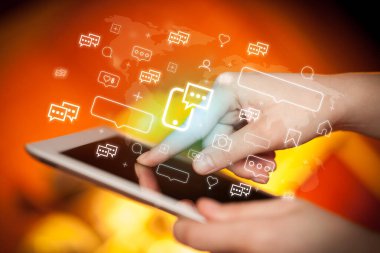 Akıllı telefon sohbet simgeleri içeren tablet kullanan bir elin yakın çekimi, sosyal medya kavramı