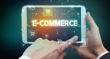 E-COMERCE yazıtları ve online alışveriş konseptiyle el ele tutuşan tabletin yakın çekimi