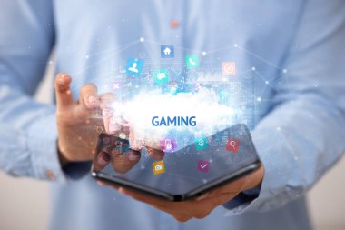 İş adamı katlanabilir bir akıllı telefon tutuyor. Oyun yazıtları ve teknoloji konsepti var.