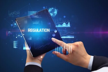 İş adamı katlanabilir bir akıllı telefon tutuyor. Üzerinde REGULAON yazıtları var. Başarılı bir iş konsepti.