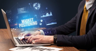 MARKET POSITIONING yazı, yeni iş konsepti ile birlikte dizüstü bilgisayarda çalışan işadamı