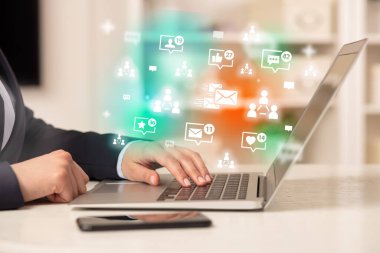 Mesajlaşma simgeleri ve sosyal medya konseptiyle dizüstü bilgisayarda sörf yapan genç kişi