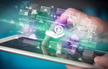 Tablet kullanan bir elin, içinden bitcoin simgeleri çıkan dijital para birimi kavramını kullanarak yakın plan görüntüsü