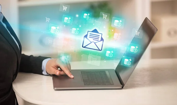 Businessman working on laptop with mail icons coming out from it, successful business concept