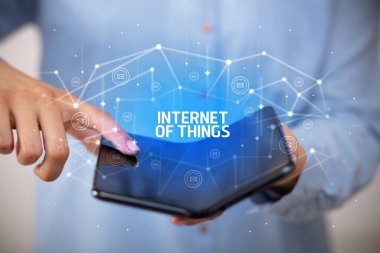 İş adamı elinde, üzerinde yeni teknoloji kavramı ve yazıtların olduğu katlanabilir bir akıllı telefon tutuyor.