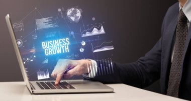 İş adamı bilgisayarında Business Growth yazıtı ve yeni iş konseptiyle çalışıyor.