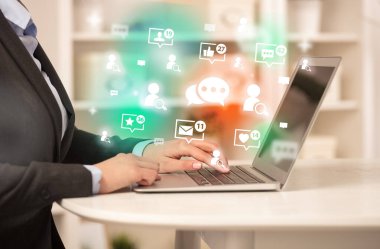 Mesajlaşma simgeleri ve sosyal medya konseptiyle dizüstü bilgisayarda sörf yapan genç kişi