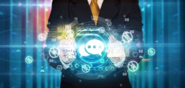 İş adamı elinde birden fazla teknoloji sembolü olan konuşma balonu simgesini tutuyor.