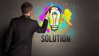 İş adamı desenli beton duvara SOLUTION yazısıyla renkli ampul çiziyor, yeni iş fikri kavramı