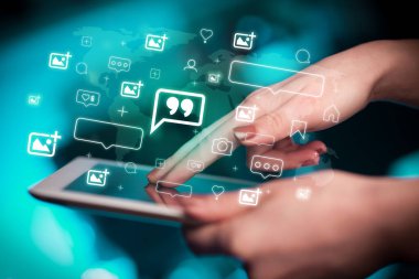 İçinden simgeler çıkan tablet kullanan bir elin yakın plan resmi, sosyal medya kavramı