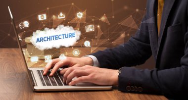 Mimari yazıtlar ve modern teknoloji konseptiyle dizüstü bilgisayarda çalışan bir iş adamı.