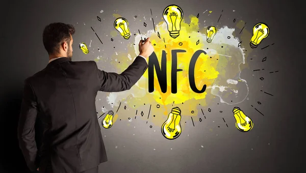 商人画五彩缤纷的灯泡用Nfc缩写 新技术理念 — 图库照片