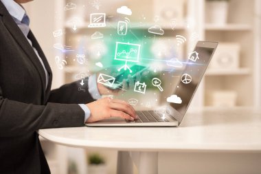 Dizüstü bilgisayarda çalışan iş adamı, içinden resim çizelgeleri çıkıyor, iş dünyası kavramı büyüyor.