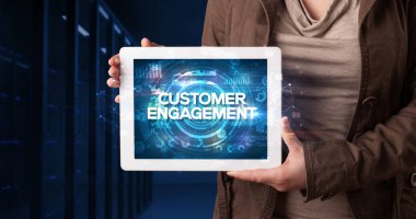 Tablet üzerinde çalışan genç iş adamı ve yazıyı gösteriyor: CUSTOMER ENGAGEMENT, iş konsepti