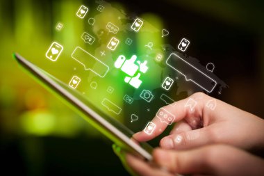 Bir elin yakın plan resmi, tablet kullanılarak, içinden sevilen simgeler çıkıyor, sosyal medya kavramı