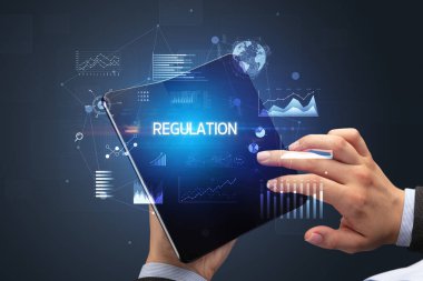 İş adamı katlanabilir bir akıllı telefon tutuyor. Üzerinde REGULAON yazıtları var. Başarılı bir iş konsepti.
