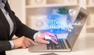 Diz üstü bilgisayarda çalışan bir iş adamının yan görünüşü SuSTAINable DEVELOPMENT yazıtları, modern iş konsepti