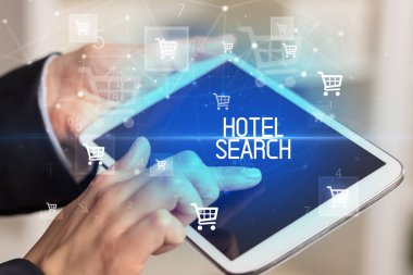 Genç kişi, HOTEL Arama yazısıyla online alışveriş uygulaması üzerinden alışveriş yapıyor
