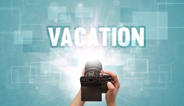 Tatil yazıtları ve seyahat konseptiyle el ele tutuşan dijital kameranın yakın çekimi