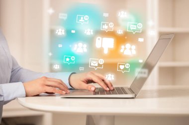 Dizüstü bilgisayarda ikonlar ve sosyal medya kavramlarıyla sörf yapan genç kişi