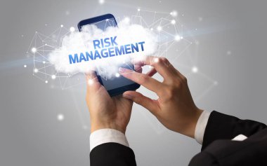 RISK MANAGEMENT yazıtlı akıllı telefona dokunan kadın el, bulut işi konsepti