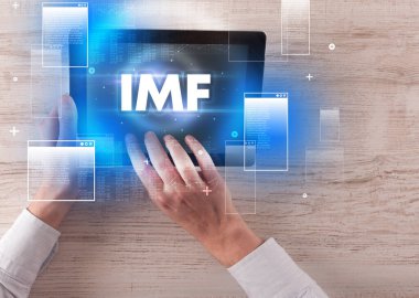 IMF kısaltması, modern teknoloji kavramı ile el ele tutuşma tabletinin yakın çekimi