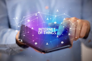 İş adamı elinde, üzerinde yeni teknoloji kavramı ve yazıtların olduğu katlanabilir bir akıllı telefon tutuyor.