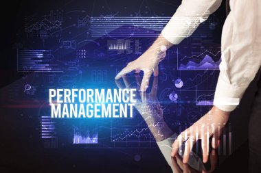 İş adamı Performans Yönetimi yazıtları ve siber iş konseptiyle büyük ekrana dokunuyor.