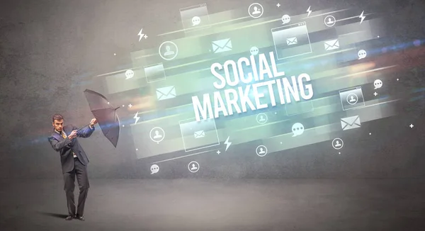 ソーシャルマーケティングの碑文から傘で守るハンサムなビジネスマン 新時代のメディアコンセプト — ストック写真