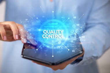 İş adamı elinde katlanabilir bir akıllı telefon tutuyor. KALİTLİK KONTROL yazıtları, yeni iş konsepti