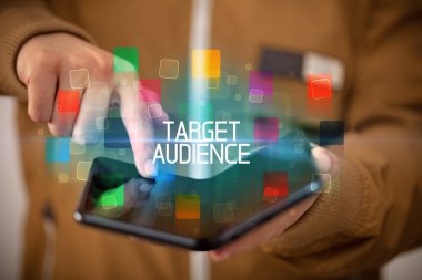 Katlanabilir bir akıllı telefon tutan genç adam TARGet AUDIENCE yazıtları, eğitim konsepti