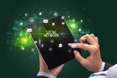 Elinde SOCIAL NETworK yazıtlı, sosyal ağ kavramlı katlanabilir bir akıllı telefon tutan bir iş adamı