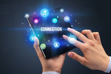 ConNECTION yazıtlı, sosyal medya kavramlı katlanabilir bir akıllı telefon tutan bir iş adamı