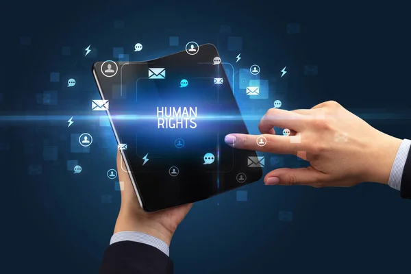 Stock image Businessman holding a foldable smartphone with HUMAN RIGHTS inscription, social networking concept