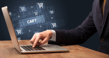 CART yazıtları ve online alışveriş konseptiyle birlikte dizüstü bilgisayarda çalışan bir işadamı