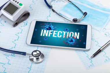 Beyaz yüzeyde INFECTION yazıtları, salgın konsepti olan tablet pc ve doktor araçları