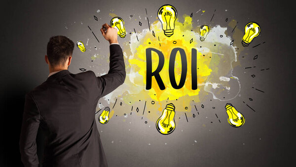 businessman drawing colorful light bulb with ROI abbreviation, new technology idea concept