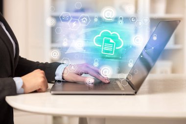 Eller dizüstü bilgisayarda bulut depolama simgeleri ve modern teknoloji konseptiyle çalışıyor.