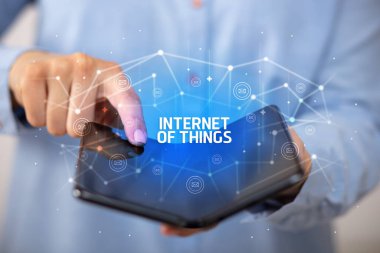 İş adamı elinde, üzerinde yeni teknoloji kavramı ve yazıtların olduğu katlanabilir bir akıllı telefon tutuyor.