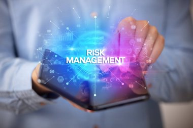 İş adamı, üzerinde Risk Yönetimi yazıtı ve yeni iş konsepti olan katlanabilir bir akıllı telefon tutuyor.